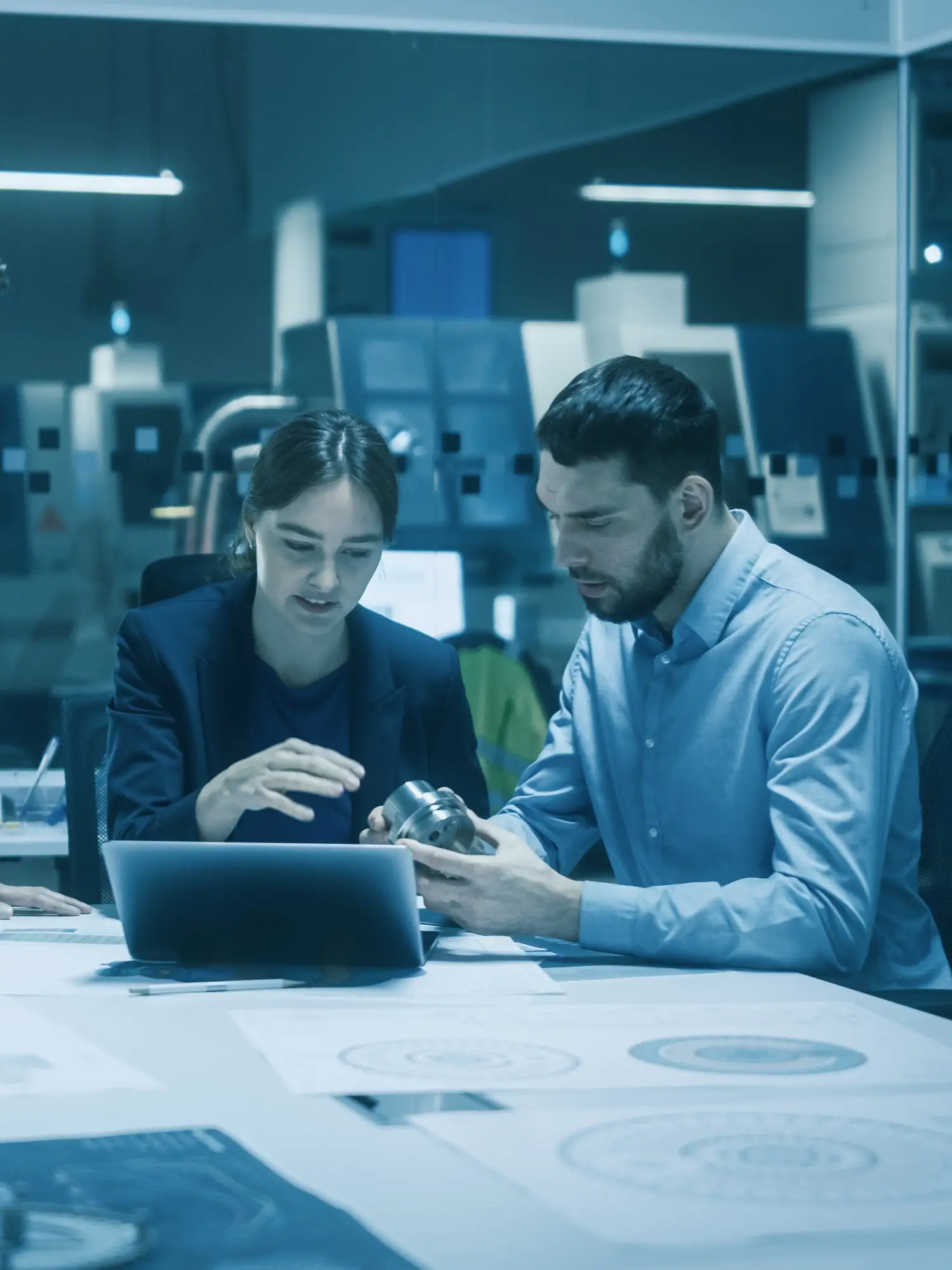 An engineer and a colleague reviewing a machined part together